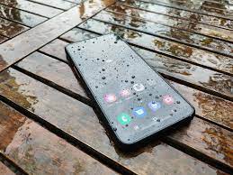 Un téléphone sur une table en bois, sous quelques gouttes de pluie.